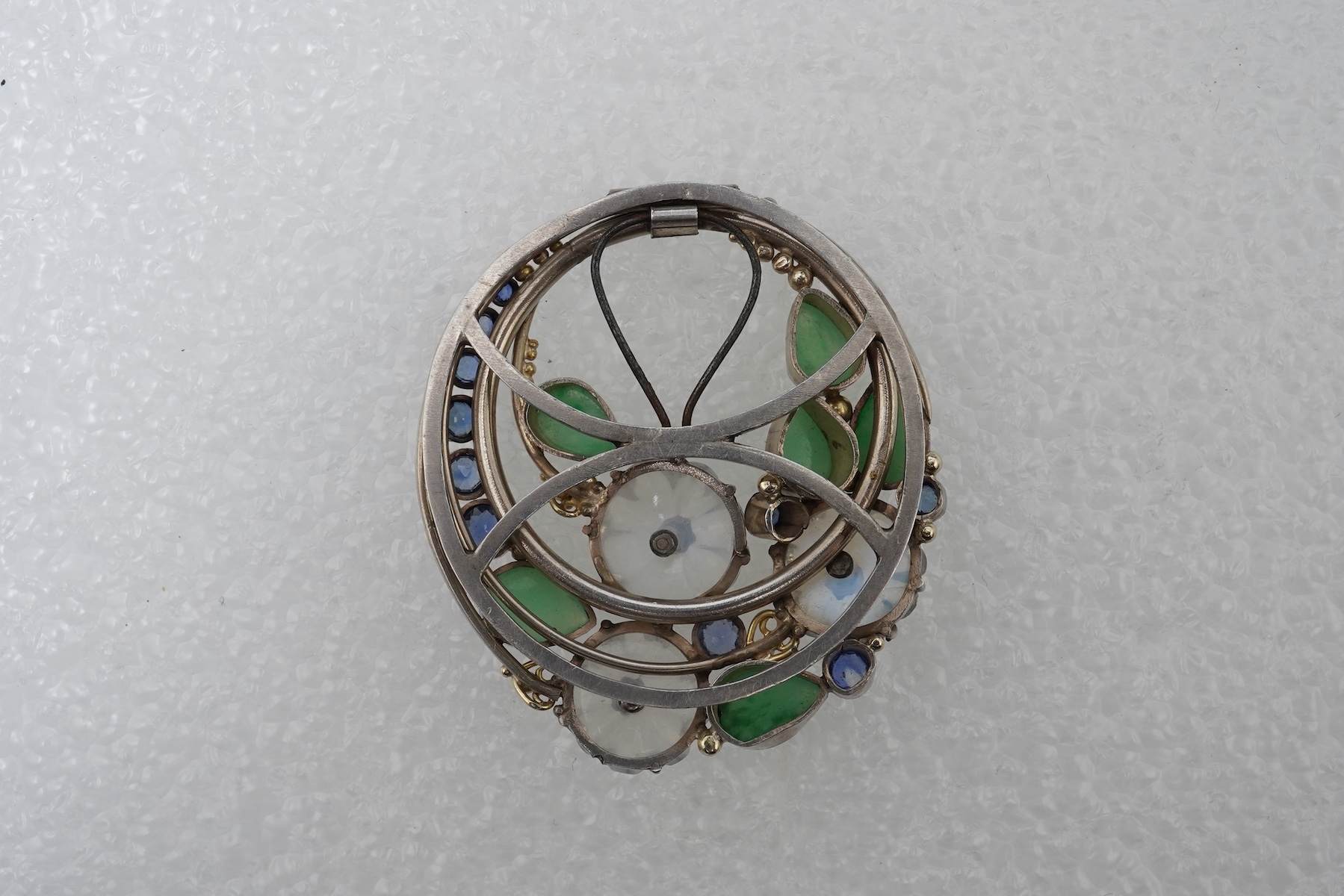 Attributed to Dorrie Nossiter (1893-1977), an Arts & Crafts moonstone, sapphire and jadeite scarf clip, 1920s